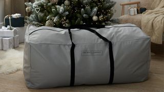 A gray duffle-like tree storage back with black handles and The White Company printed in black text on the bag, for the best Christmas tree storage bags.