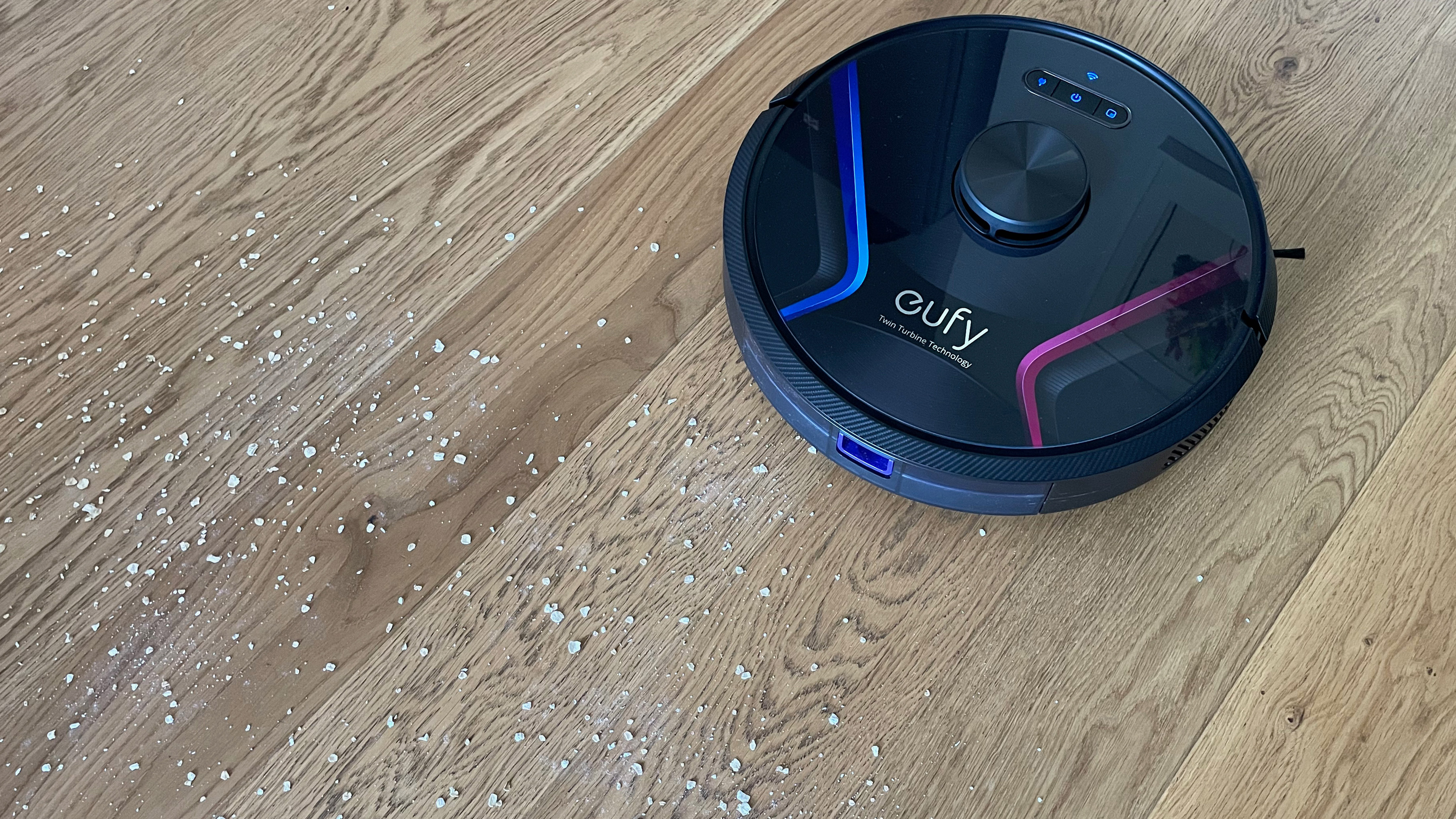 The Eufy RoboVac X8 vacuuming up oats from a wooden floor