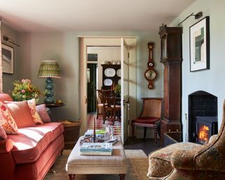 traditional living room with gray-green walls, understated red sofa and upholstered ottoman