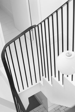 The black stair rail with the white walls and floors