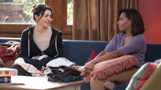 Amelia and Maggie smile at each other on the couch in Grey's Anatomy Season 22 episode "We Built This City."