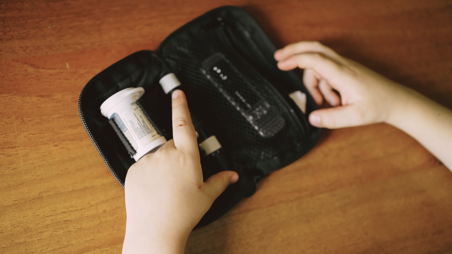 a young child with diabetes opens their glucometer kit