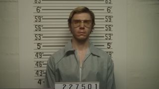 Evan Peters as Jeffrey Dahmer getting a mugshot taken at the police station.