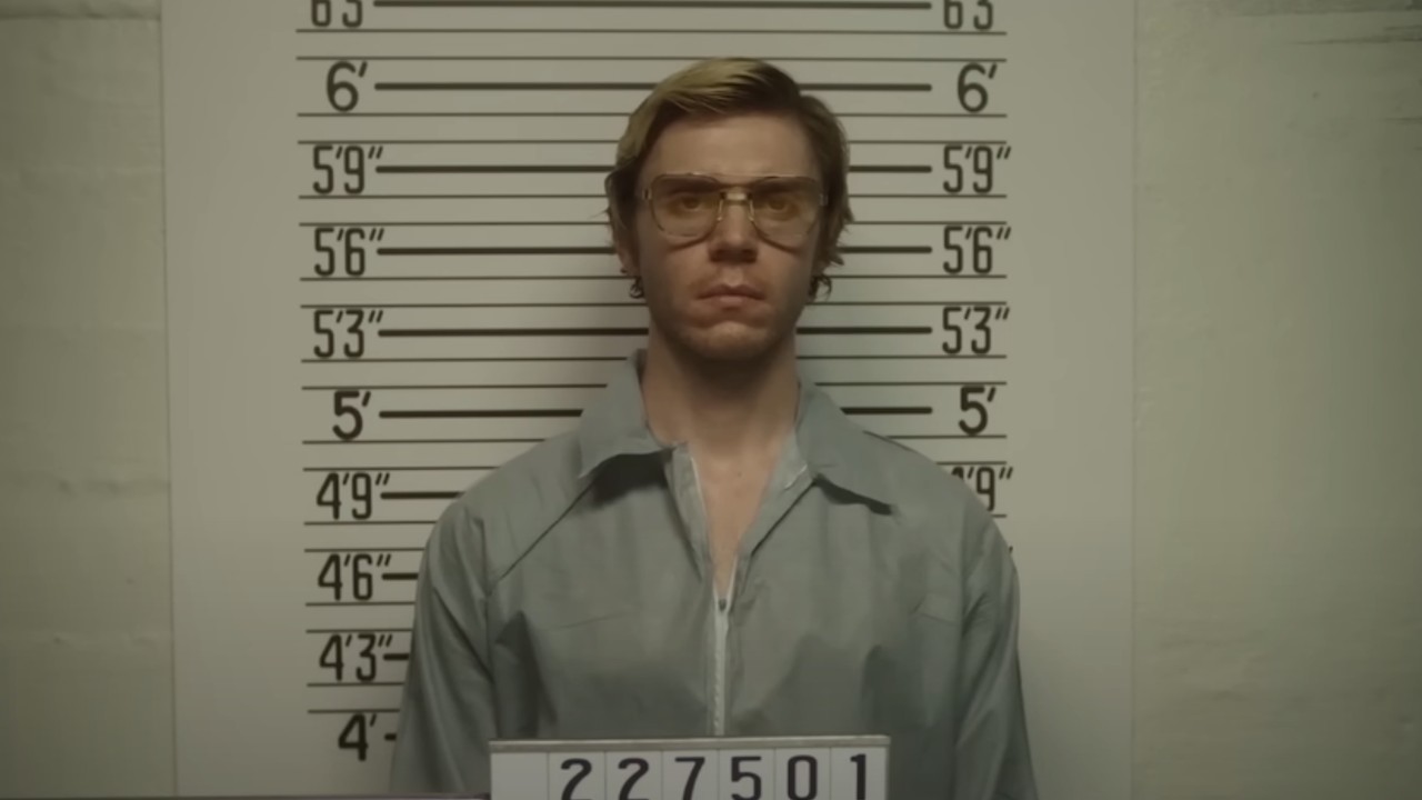 Evan Peters as Jeffrey Dahmer receiving a mugshot at the police station.