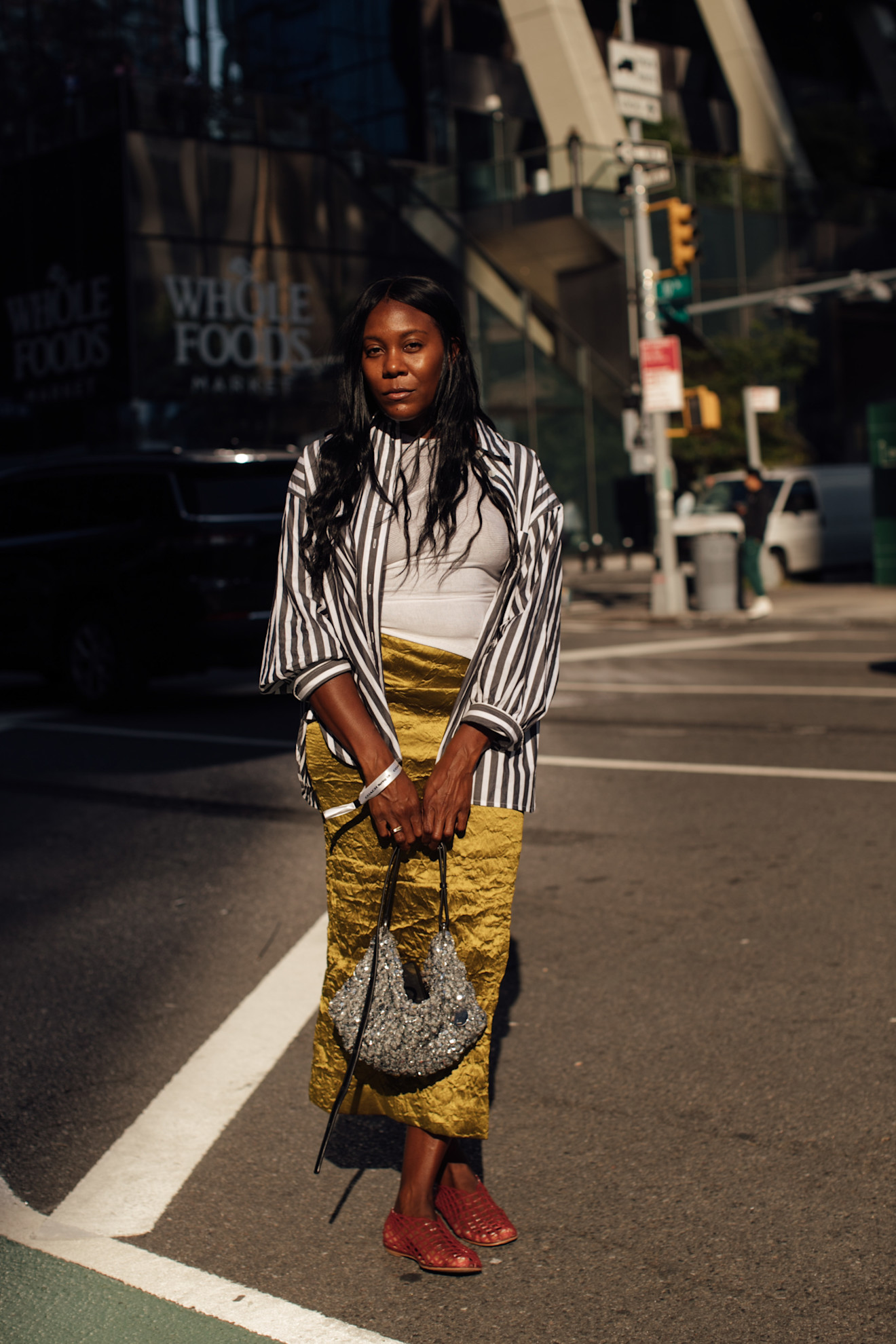 A new york fashion week spring 2025 attendee wearing a striped shirt, green skirt, and jelly shoes