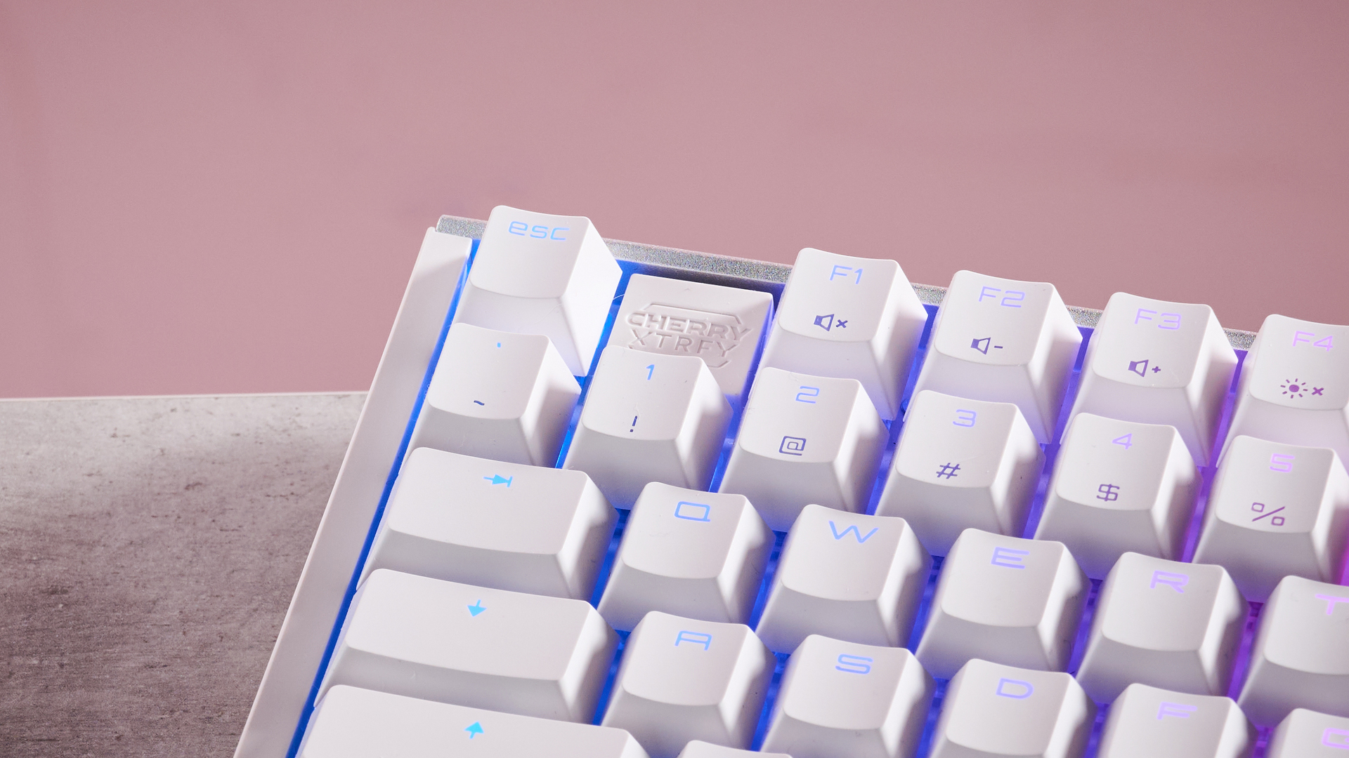 Close-up of top left corner of Cherry XTRFY MX 3.1 on desk with pink background