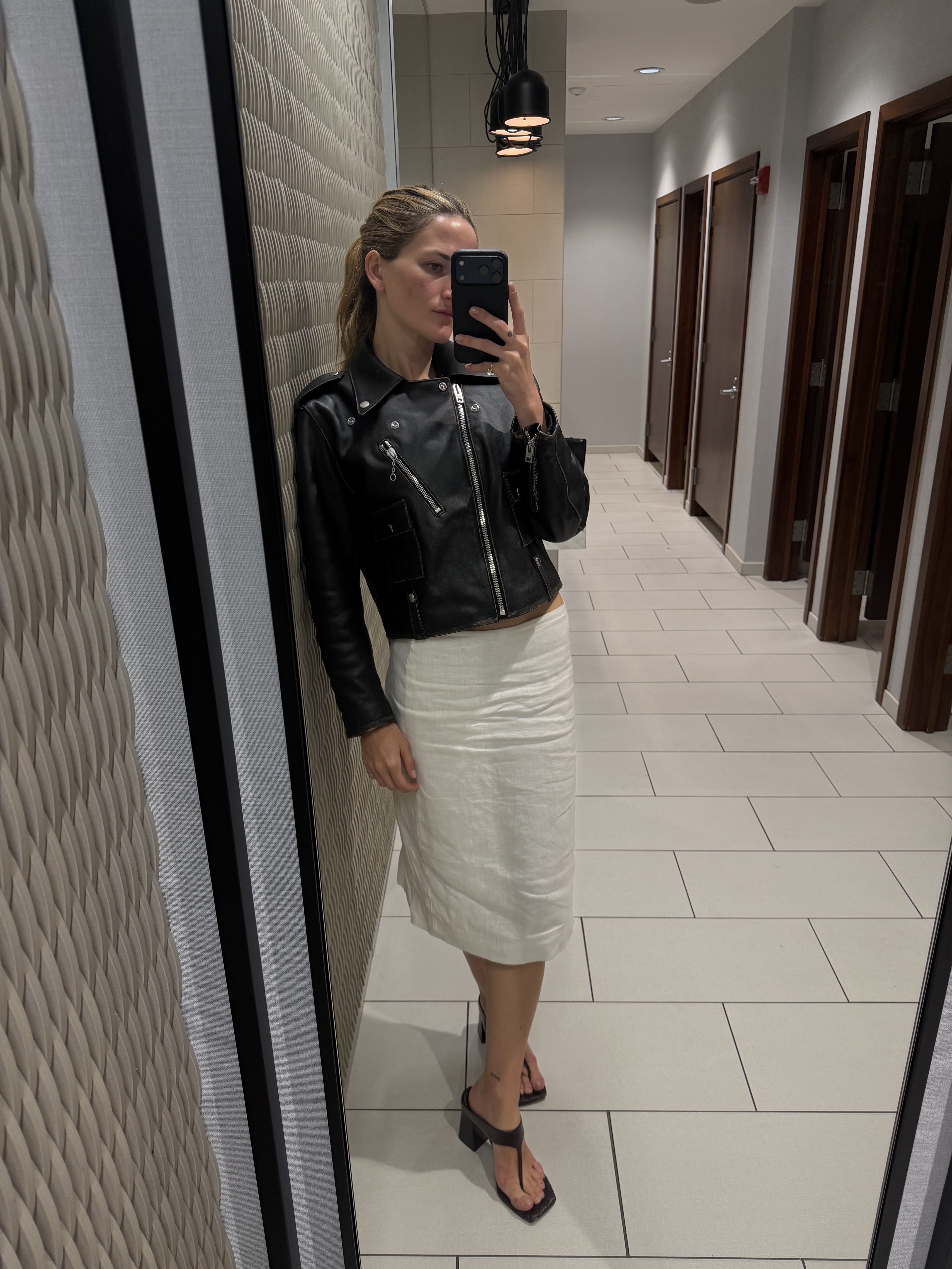 Eliza Huber wearing a leather jacket, white skirt, and burgundy heels in Indianapolis.