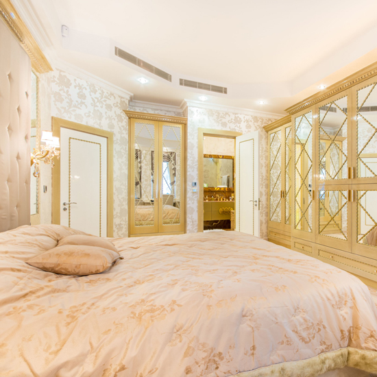 master bedroom with printed wall and giant studded headboard with cupboards