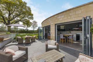 Patio with bifolding doors leading into the kitchen of this hobbit house eco home