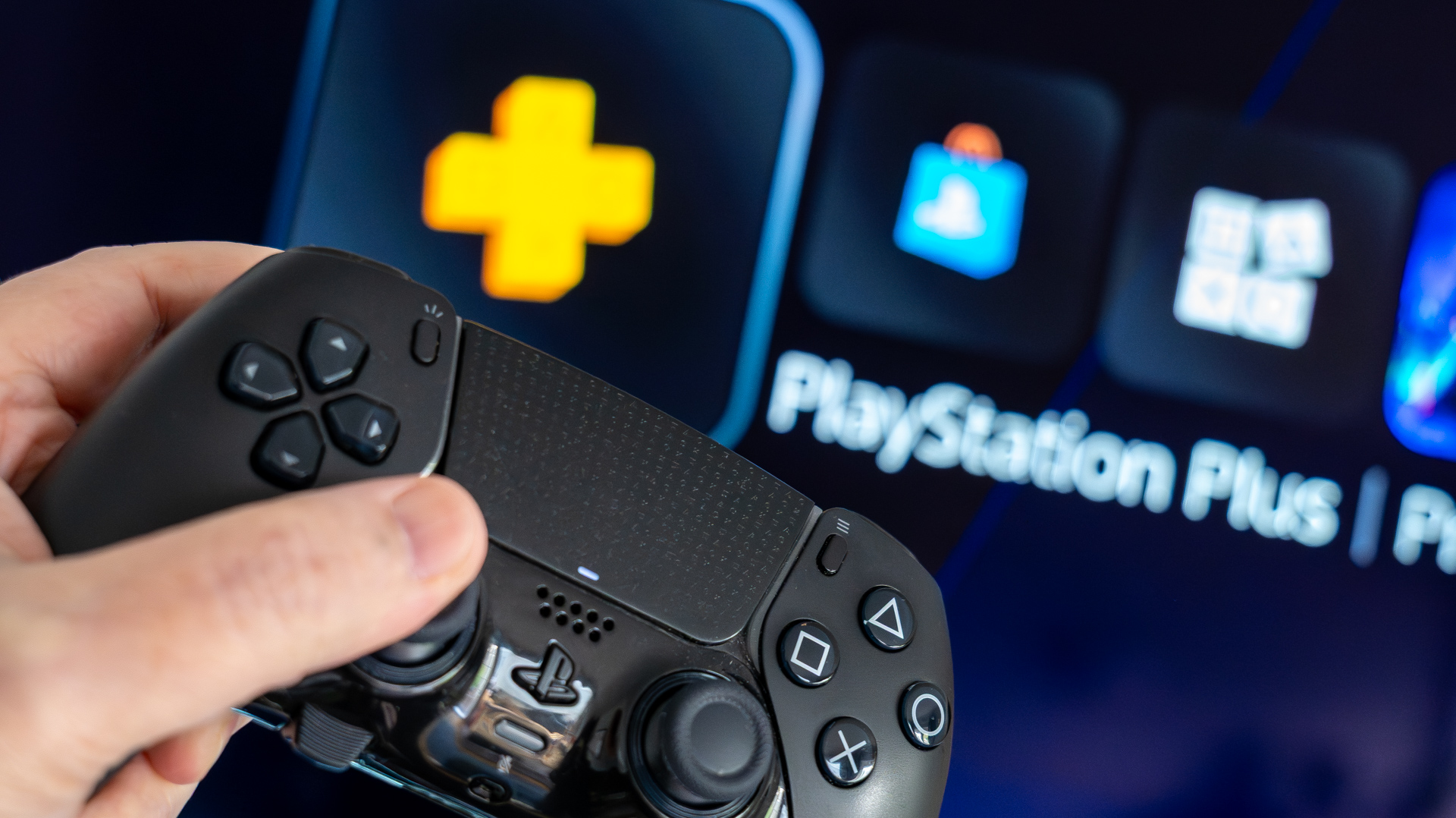PS Plus running on a Philips TV with a black DualSense Edge controller being held in the foreground