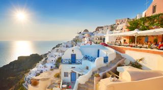 Afternoon view at Oia Town (northern part of the Santorini) with sun in the background, Santorini Island, Cyclades, Greece