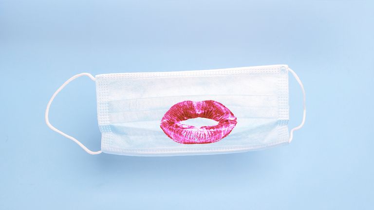 Medical mask with print of female lipstick kiss lips on blue background. Prevention and protection of the population during an epidemic, Corona virus (COVID19), colds and viral flu