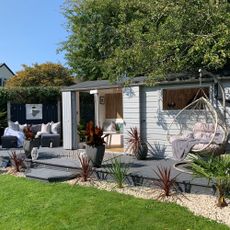 Garden shed on raised decking with hanging egg chair