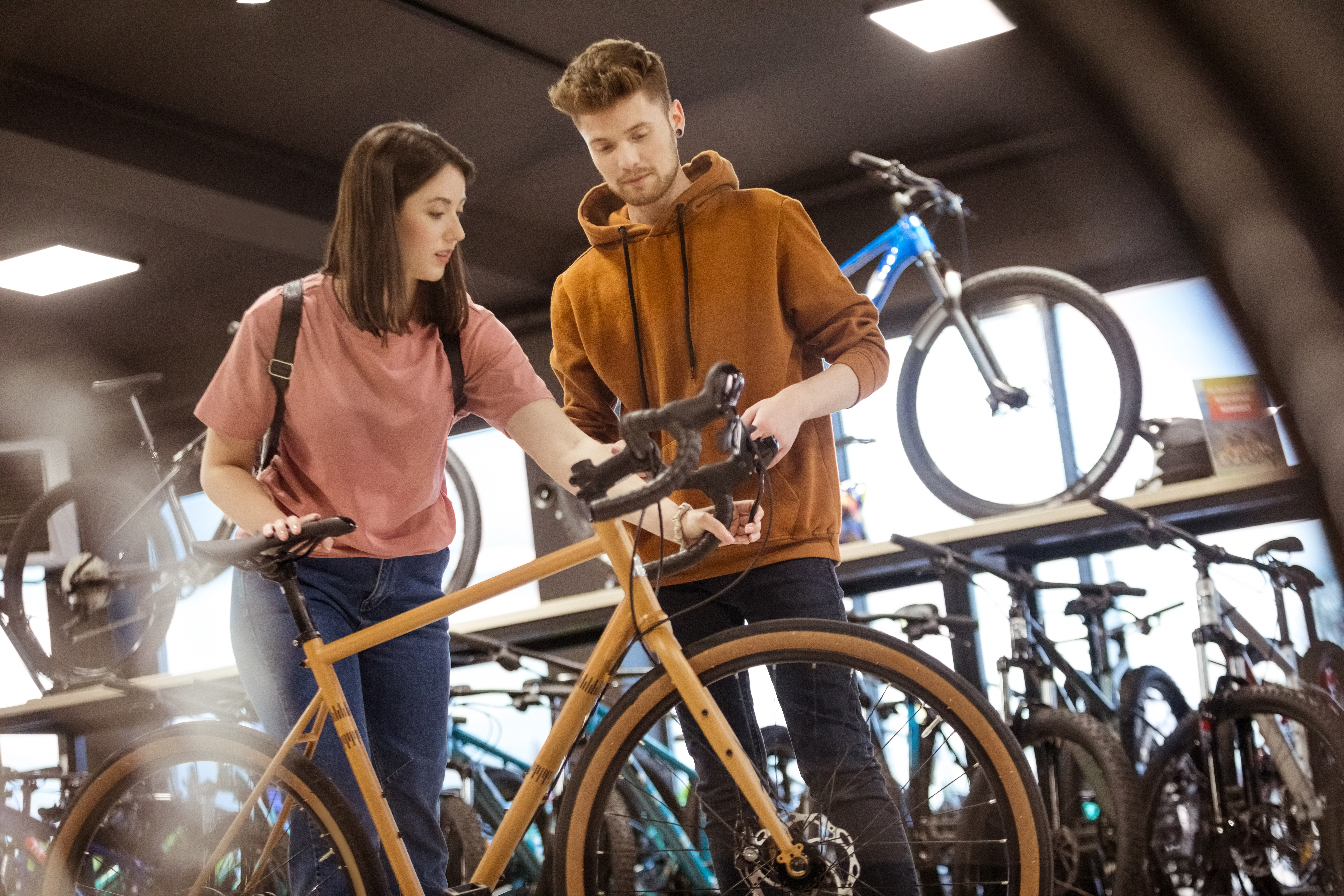 A man and a woman test out a yellow bike in a shop