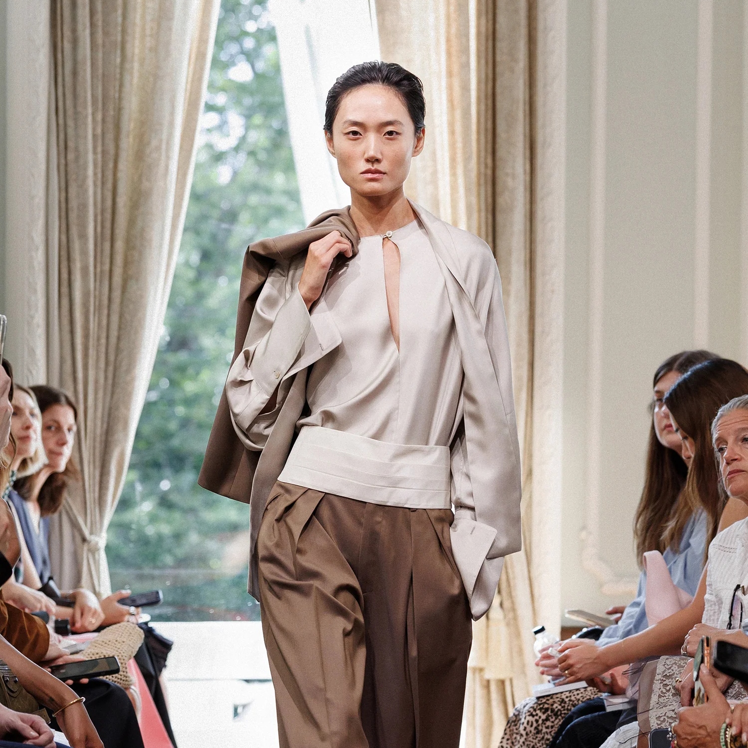 a Kallmeyer model walking the ss27 runway wearing a cream blouse and matching cummerbund