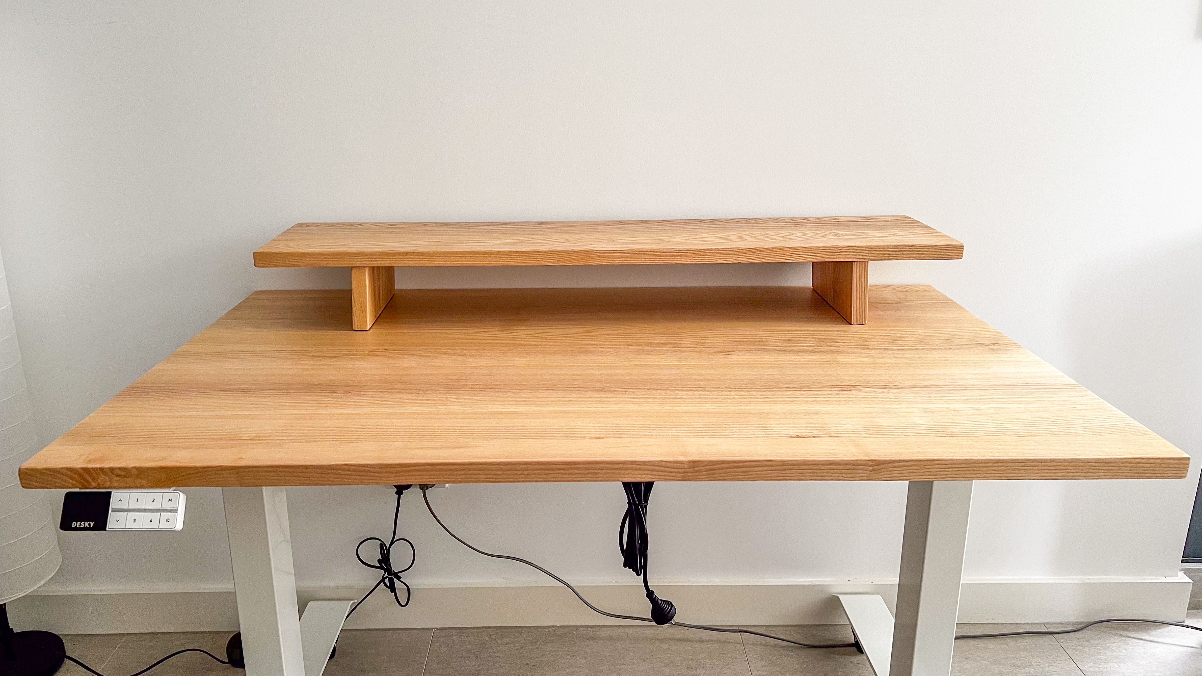 Desky Dual Bamboo standing desk in light bamboo finish with matching wooden monitor stand