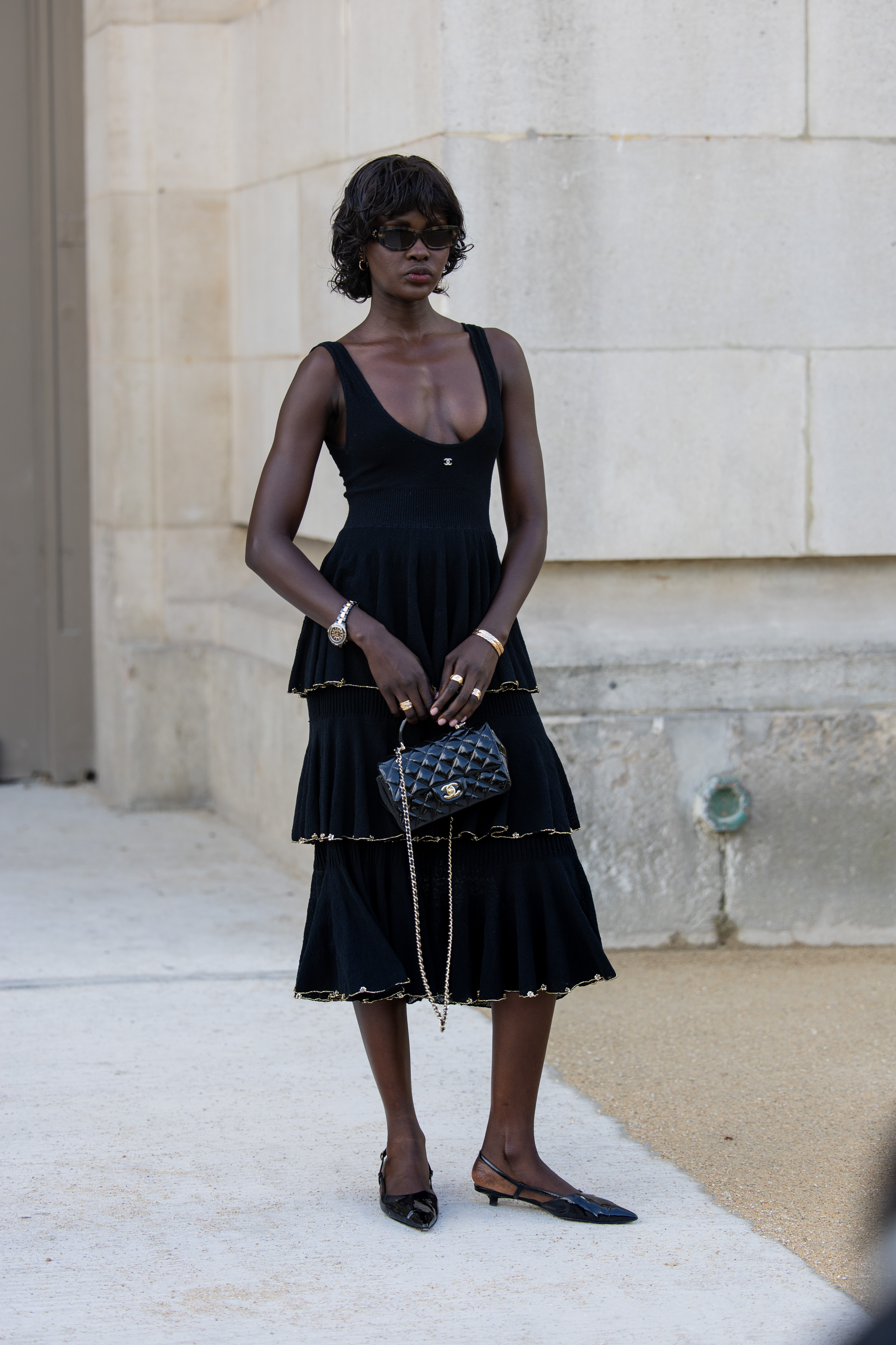 Una invitada luce un vestido negro con volantes y un bolso en la entrada de Chanel durante la Alta Costura Otoño/Invierno 2025/2026 en el marco de la Semana de la Moda de París.
