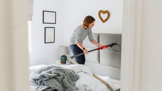 Woman vacuuming a bedroom