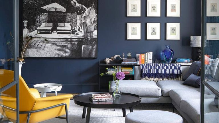 A navy blue painted living room with a bright yellow couch