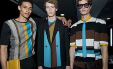 Three male models wearing clothing by Salvatore Ferragamo in colourful shades.