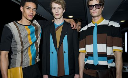 Three male models wearing clothing by Salvatore Ferragamo in colourful shades.