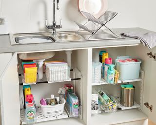 Adjustable under kitchen sink storage in white with household cleaning items