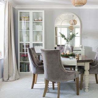 grey dining room with velvet chairs and arched mirror