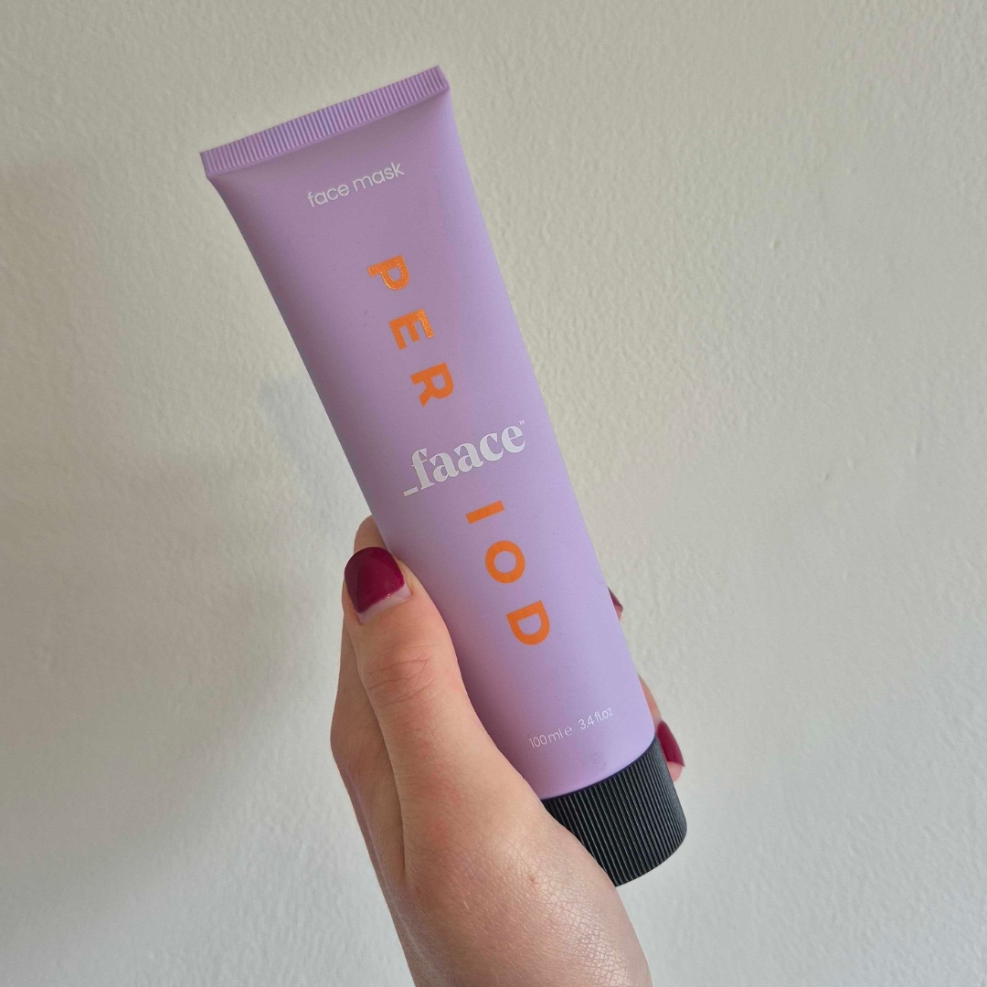 A close-up of Digital Beauty Writer, Naomi Jamieson holding up the _Faace Period Gel Face Mask, in front of a cream wall
