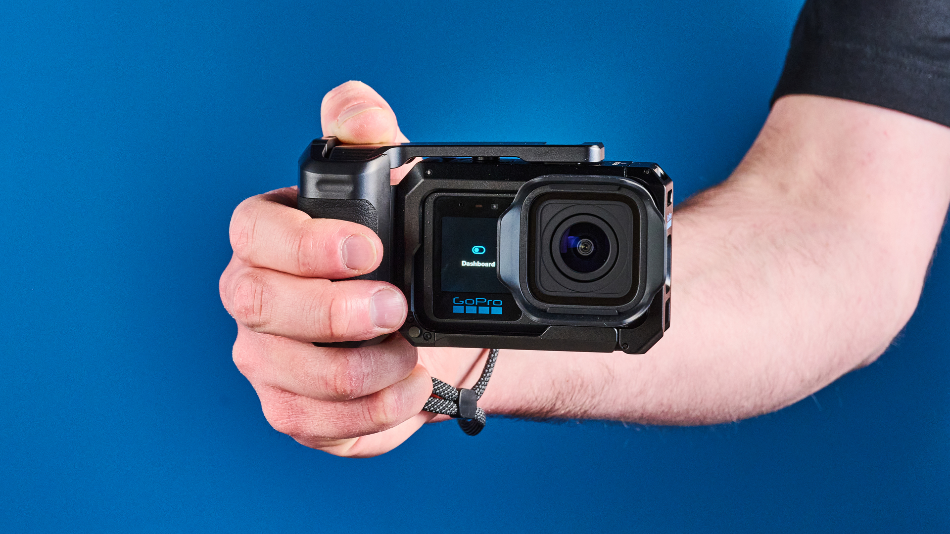 The GoPro Mission 1 Pro in hand with a camera grip, against a blue background