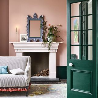 skirting board colour ideas, pink living room with dark green woodwork, coloured skirting, vintage rug, grey mirror, stripe sofa