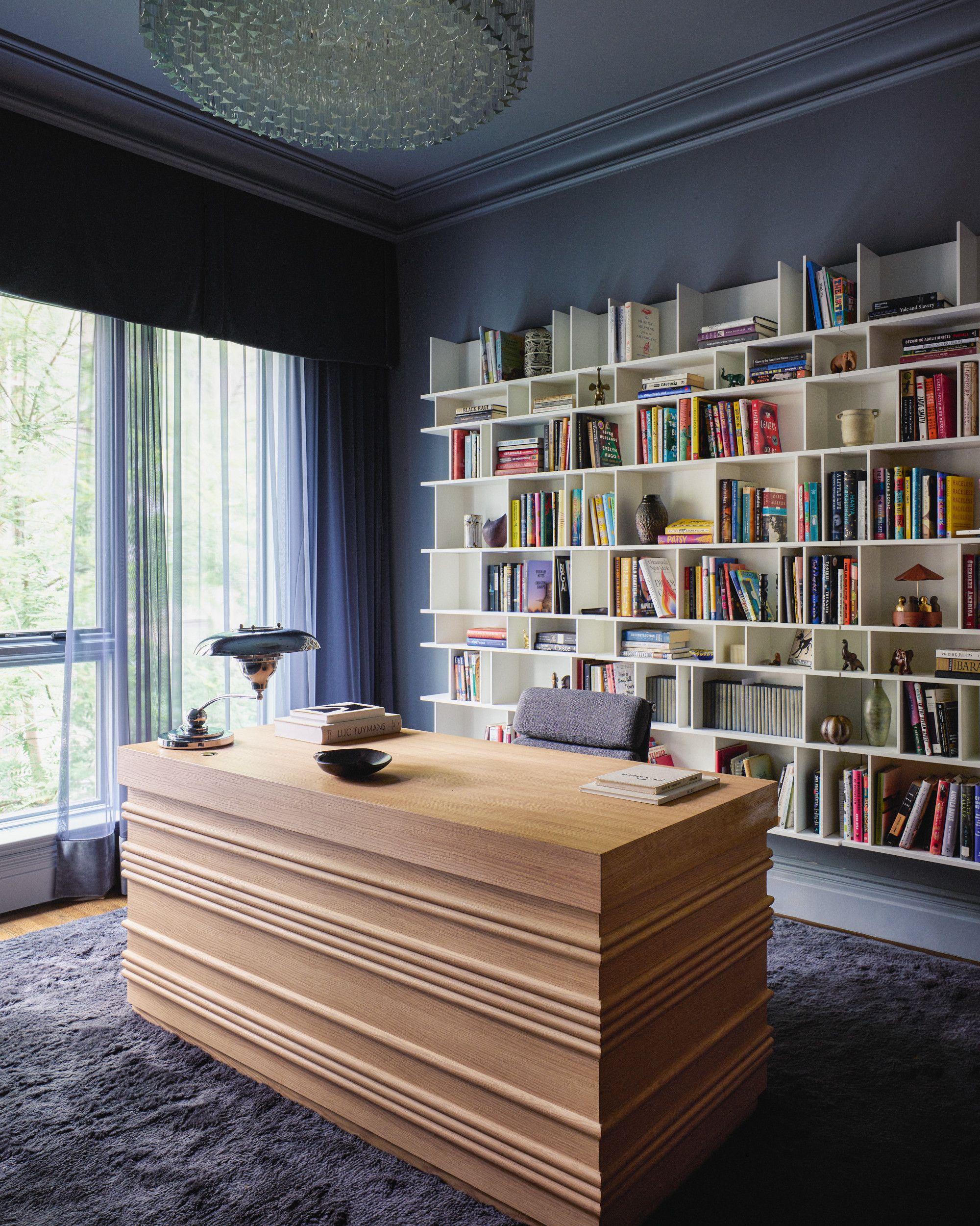 Blue office with white bookshelves and tiered wooden desk