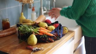 Woman washing fruit by the sink in a kitchen