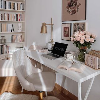 Bright WFH setup with white desk, neutral chair, roses and a large print