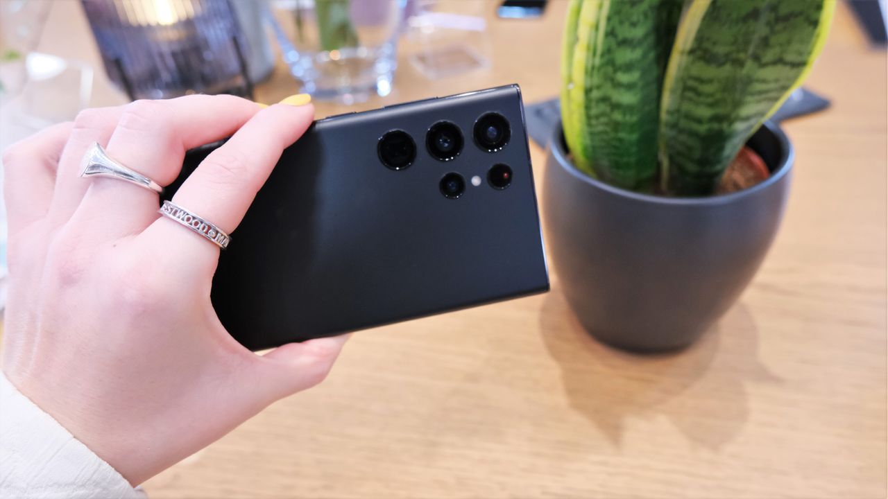 Samsung Galaxy S22 Ultra in a woman&#039;s hand with rear camera lenses on display