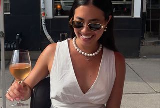 Woman in white top and necklace.