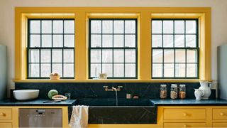 yellow kitchen with steel glazed windows and black worktops to show bright paint color ideas for a kitchen