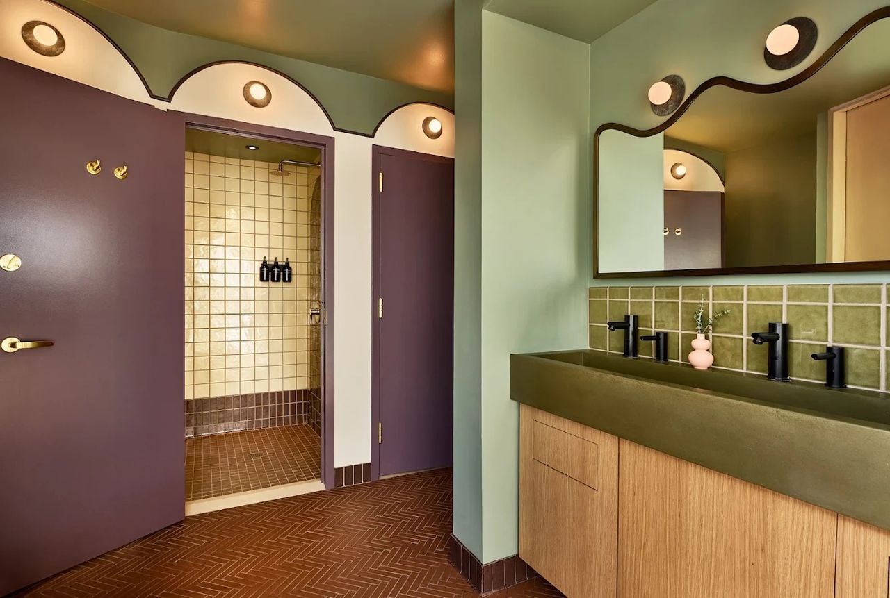 A purple, mint green, and brown bathroom boasts wavy playful lines and spherical Art Deco lighting.
