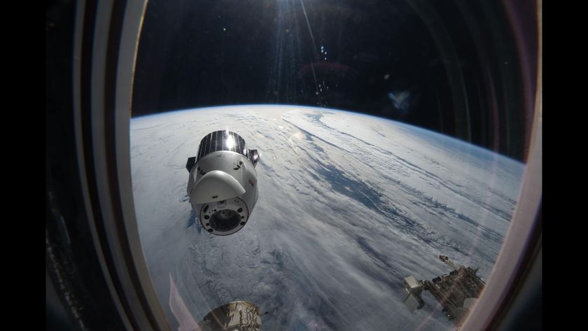 A view out of the window of the ISS sees the SpaceX Dragon capsule with Earth in the background. 