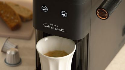 Hotel Chocolat Podster coffee machine pouring coffee into white mug