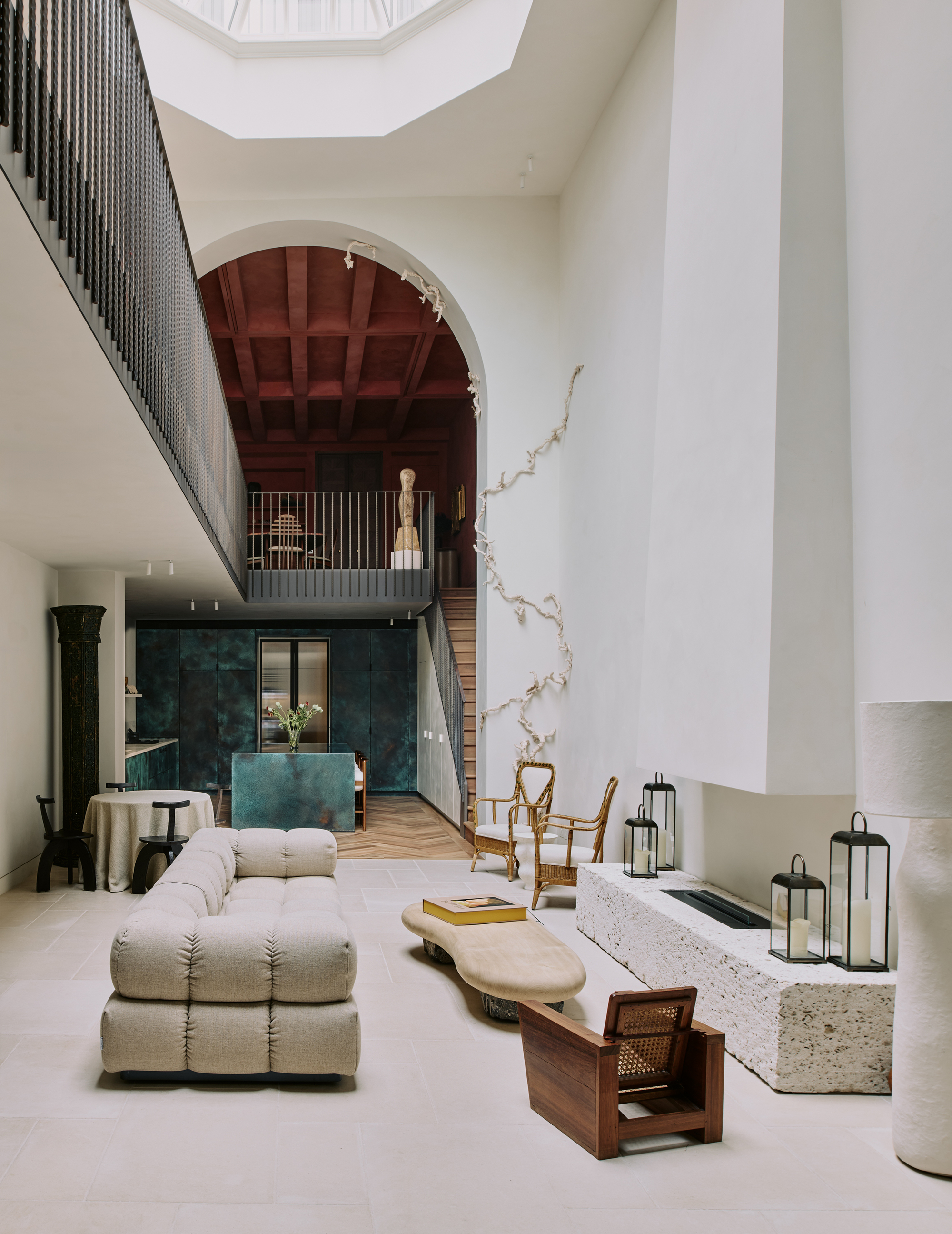 Image of a luxurious white atrium with high ceilings and an open floor plan that leads to a teal kitchen and a staircase to a red room upstairs.