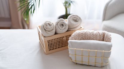 Rolled up and folded towels in two baskets on a bed