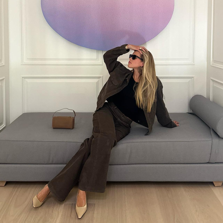 Sofia Richie Grainge wearing The Row brown '90s bag while sitting on grey couch.