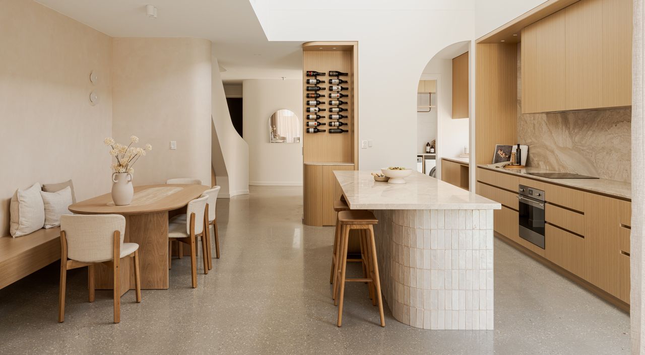 An open kitchen a small seating nook, light wood cabinets and natural flooring