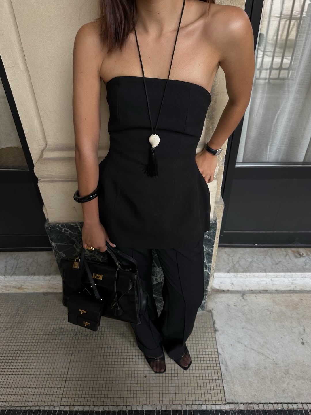 Woman in a black top and long necklace