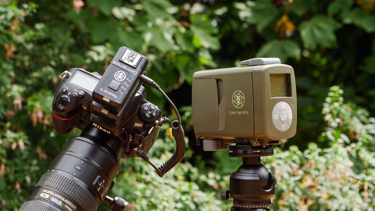 Camtraptions Camera Trap device outdoors alongside a Nikon DSLR camera