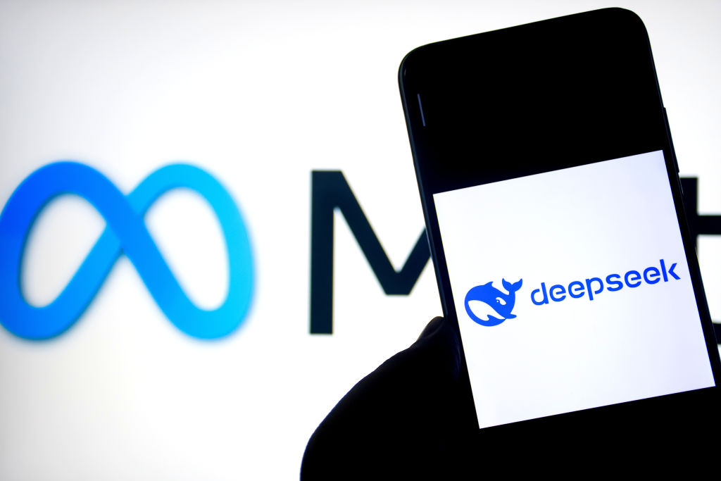 Deepseek logo is seen displayed on a smartphone with a Meta logo in the background