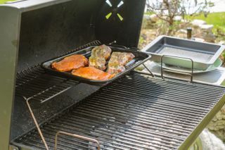 A gas grill with a griddle attachment cooking meat
