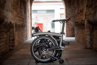 A titanium Brompton, folded up in an alleyway