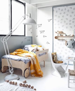 Nursery ideas with mural wallpaper, a small wooden bed and gray and yellow soft furnishings.