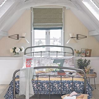 attic bedroom with white window and pillows on bed